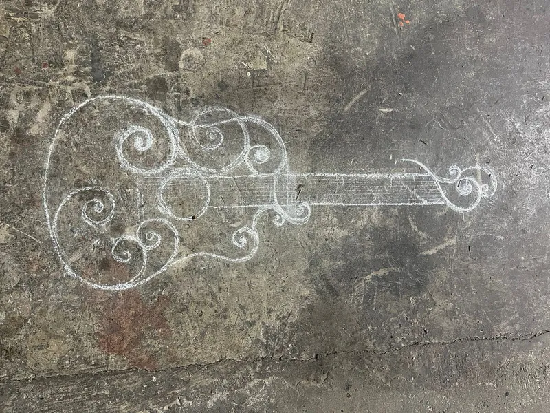 Contorno de una guitarra con espirales, dibujado con tiza en el suelo del taller.
